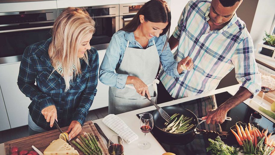 Friends laugh and cook on electric stovetop