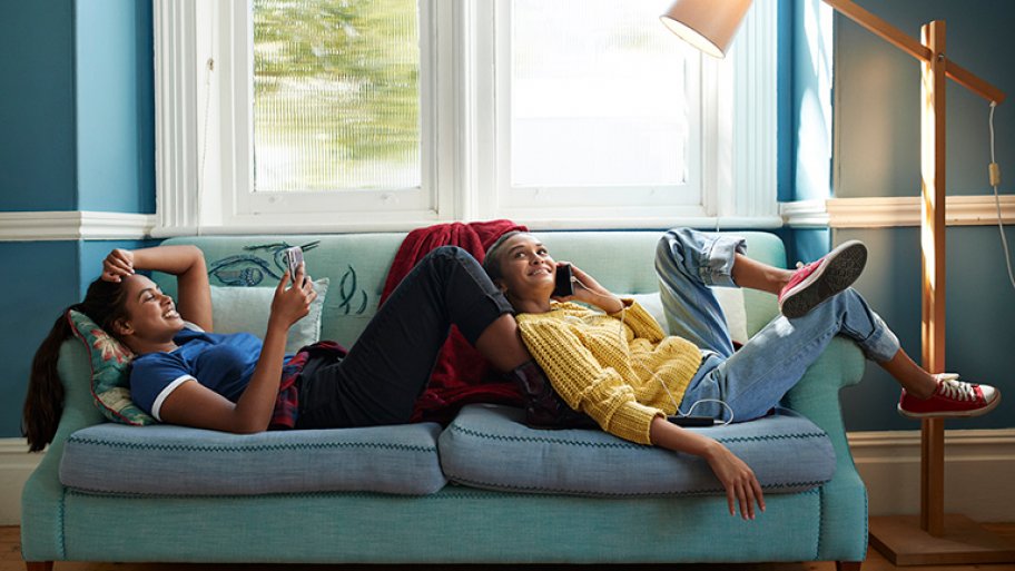 Two girls laugh in room with dark walls and light trim