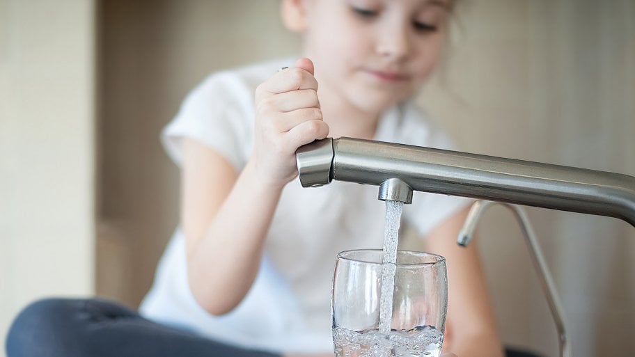 Little girl pours water into glass