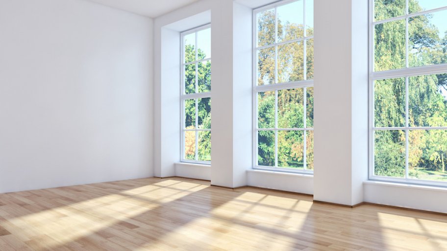 three sunny windows of an empty room overlooking trees