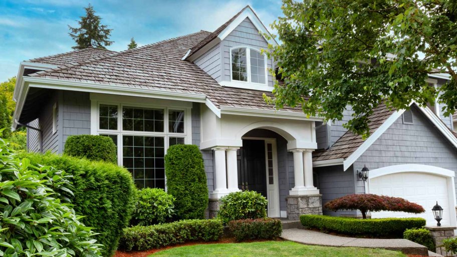 A house with a cedar shake roof and lush gardens