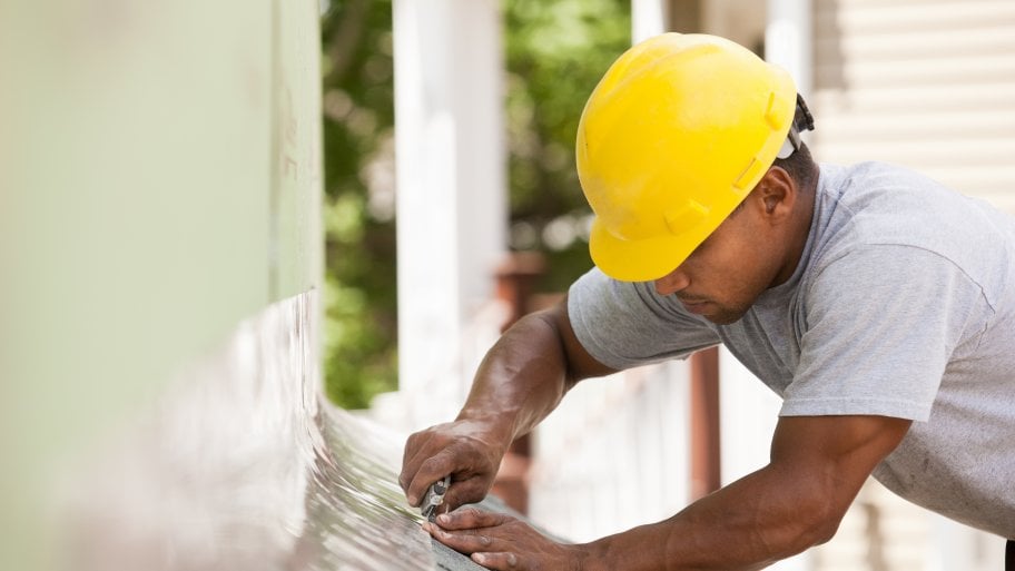 A man in construction gear installing roof flashing