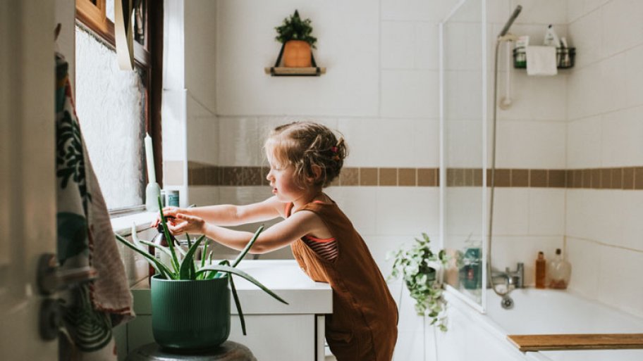 little girl washing hands in bathroom with plants