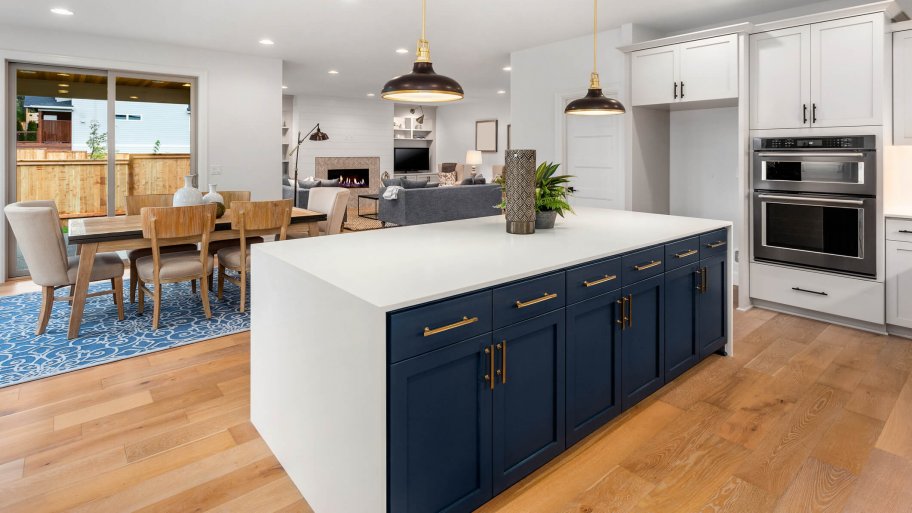 beautiful kitchen in new luxury home with large island, pendant lights, and hardwood floors. Shows dining area and living room