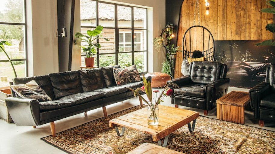 a midcentury modern style sofa in a loft style livingroom with wood accents, a wood wall, and hanging lighting