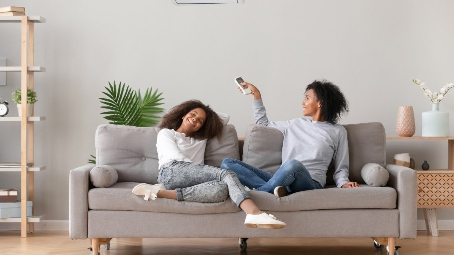 mother and daughter sit on couch in living room smiling and enjoying air conditioning