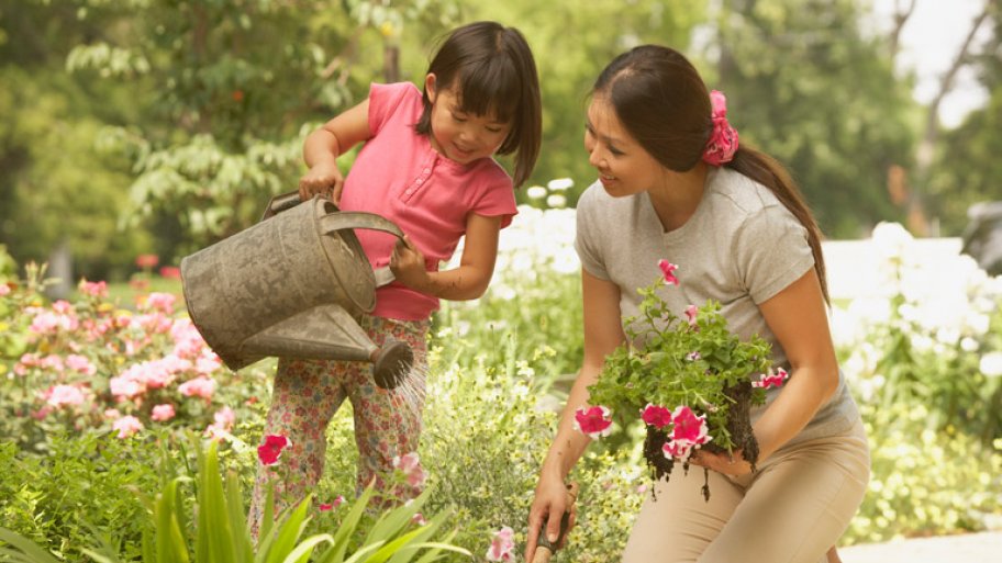 A mother and her daughter planting and watering their garden