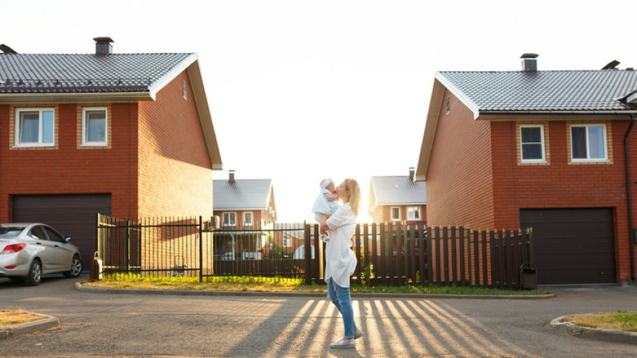 Mother kissing baby outside a row of townhomes Mother kissing baby outside a row of townhomes
