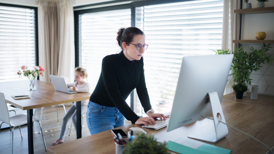 A mother working on her desktop while daughter using a laptop