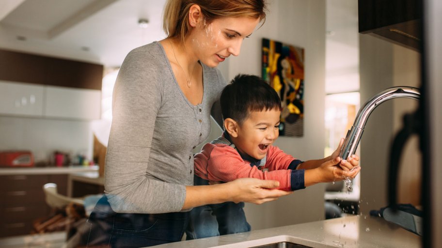 A mother helping her son to wash his hands
