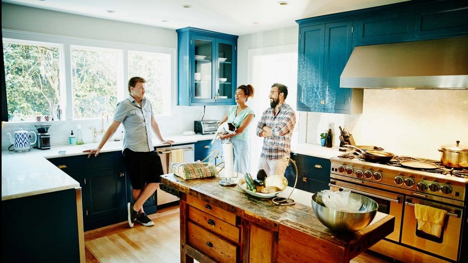 Friends talk in kitchen with painted cabinets