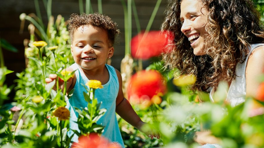 a woman and child smiling and laughing in garden with flowers