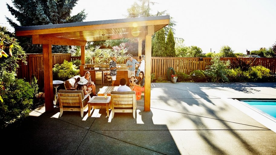 people lounging under pergola on home patio next to pool