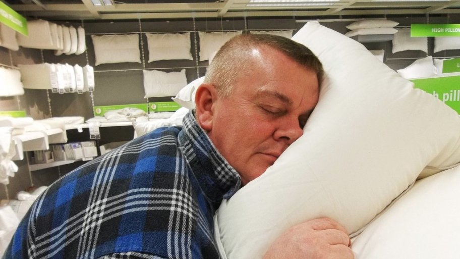A man tests out a pillow at a store display