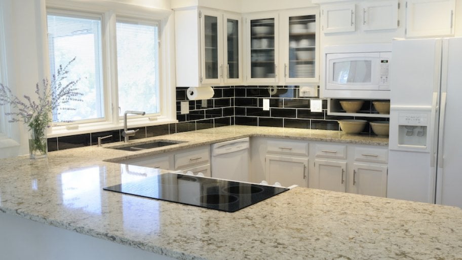 modern kitchen with white cabinets, black backsplash, and quartz countertop