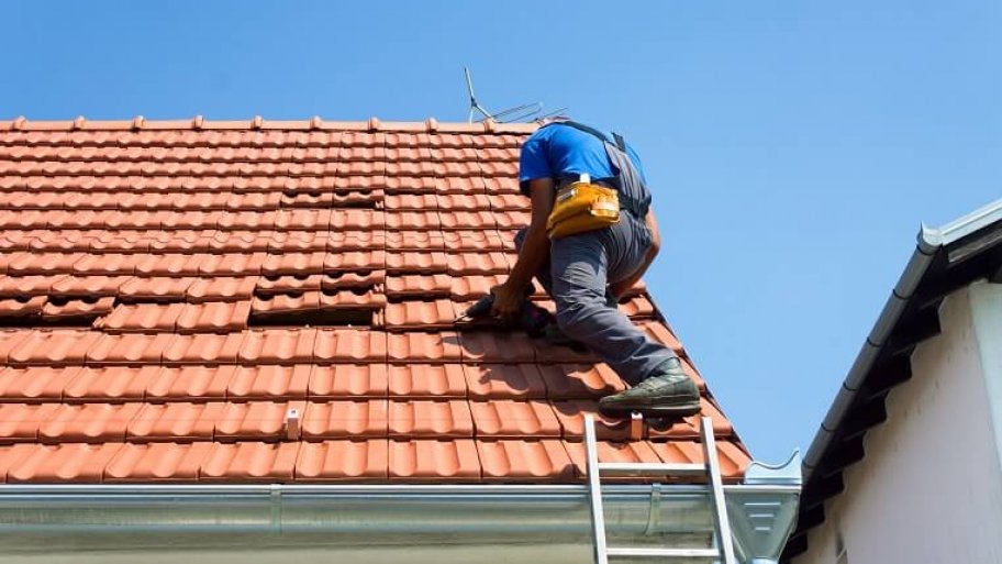 Roof repairman fixing a tile roof
