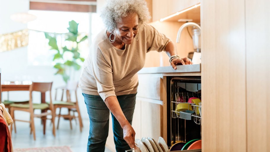 A senior woman loading the dishwasher with dishes