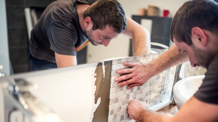 A tile contractor installs backsplash in bathroom renovation (Photo by Hoda Bogdan - stock.adobe.com)