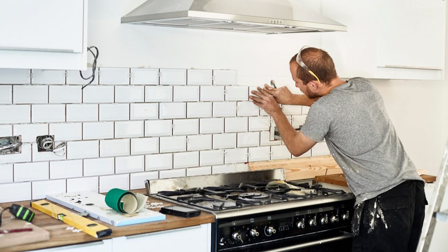 Man tiles backsplash in kitchen