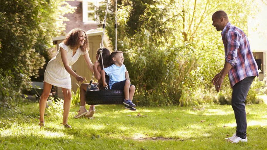 Parents Pushing Children On Tire Swing