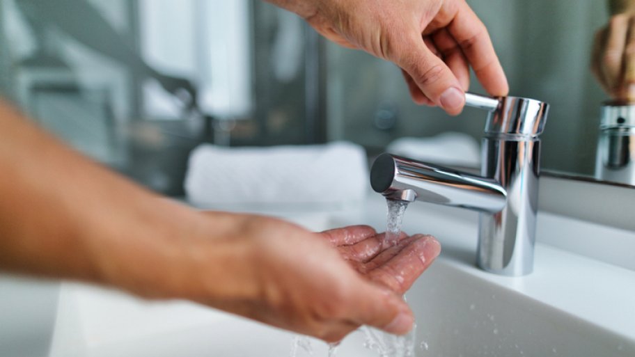 Man testing water pressure in bathroom sink