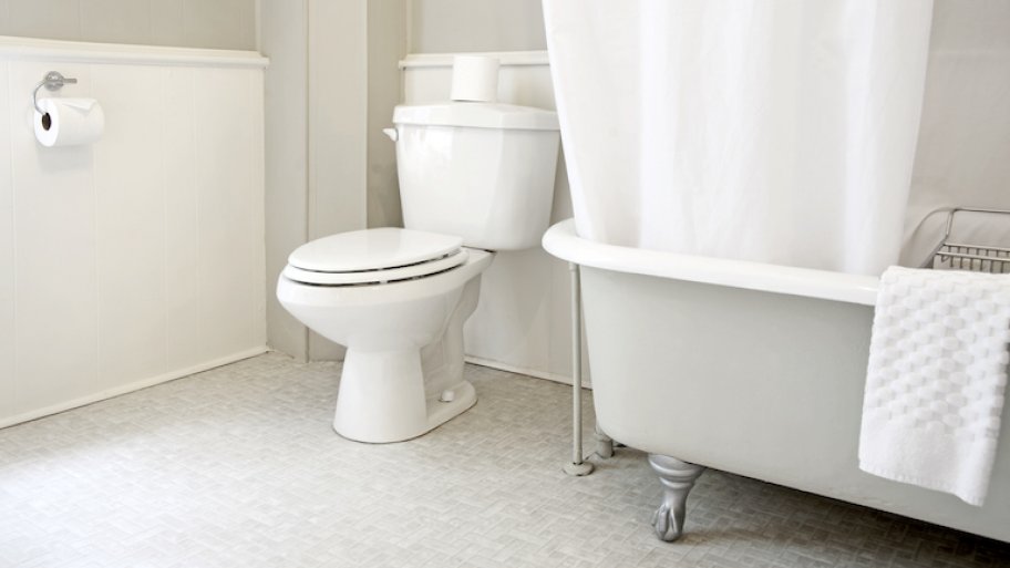 shot in white bathroom of white toilet and partial view of bathtub with white accents