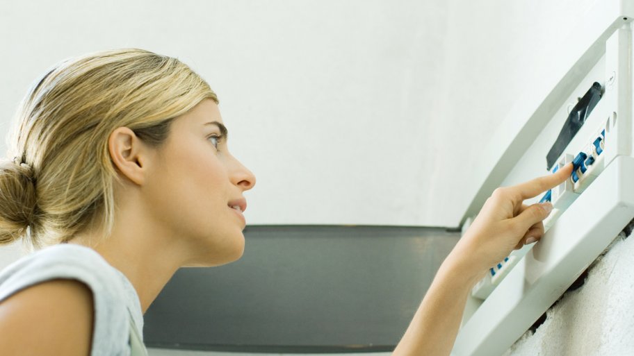 A woman looking at her house’s fuse box