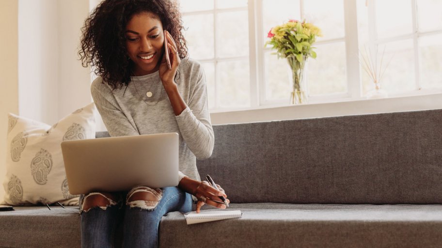 A woman talking on the phone while looking at her laptop