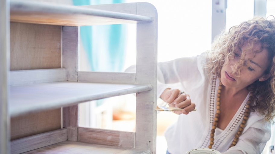 Woman painting cabinet white with chalk paint Woman painting cabinet white with chalk paint
