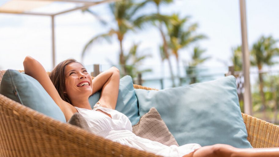Women lounging in outdoor rattan chair with blue pillows