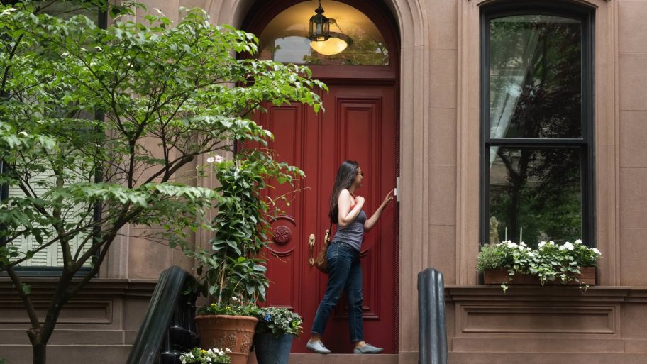 A young woman ringing the doorbell of a house (Photo by Lauren Lee/Stocksy - stock.adobe.com)