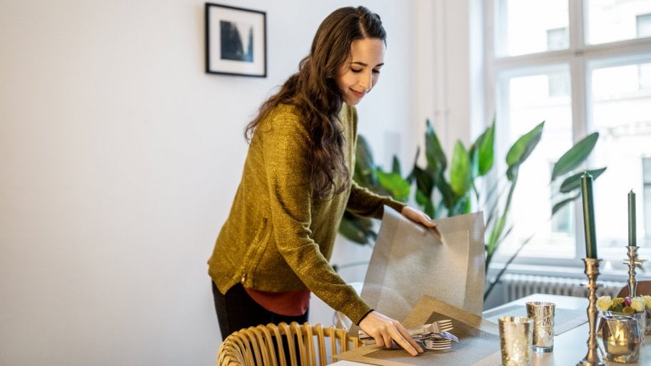 A woman setting the table by placing placemats