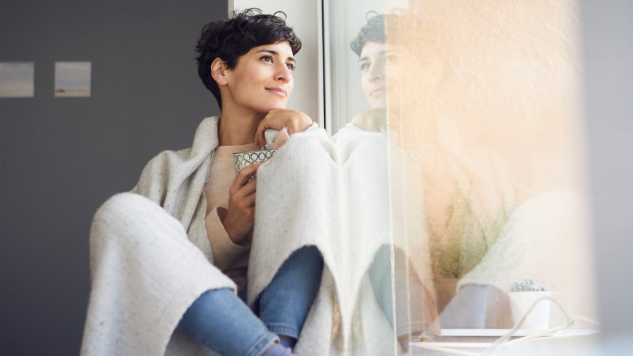 Woman covered in a blanket sitting by the window