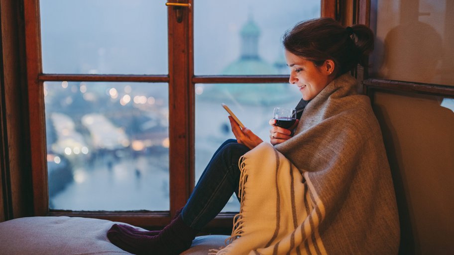 A woman wrapped in a blanket checking her phone