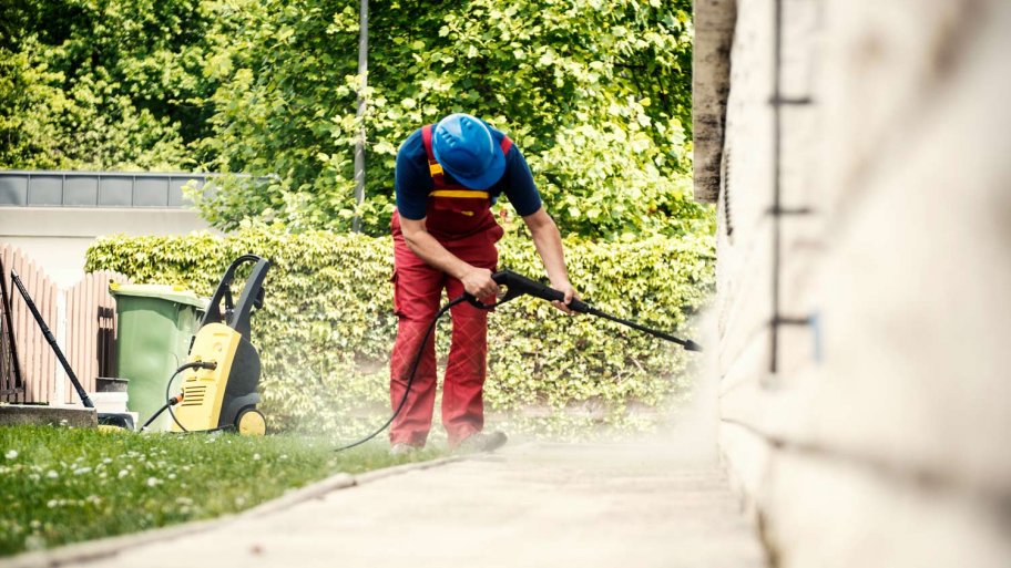 A worker cleaning the exterior of a house with a pressure washer