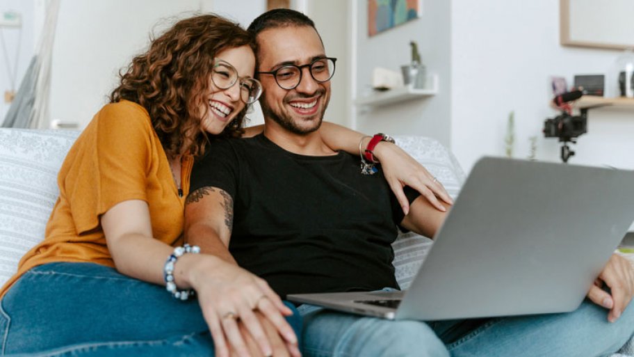 young couple sitting on couch with laptop