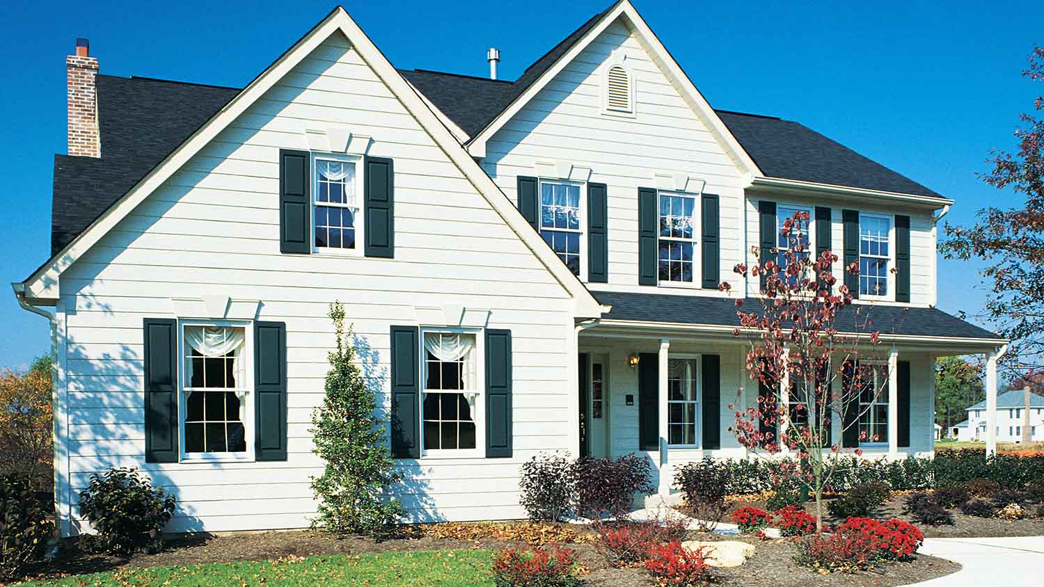White siding and green window shutters installed on a suburban house