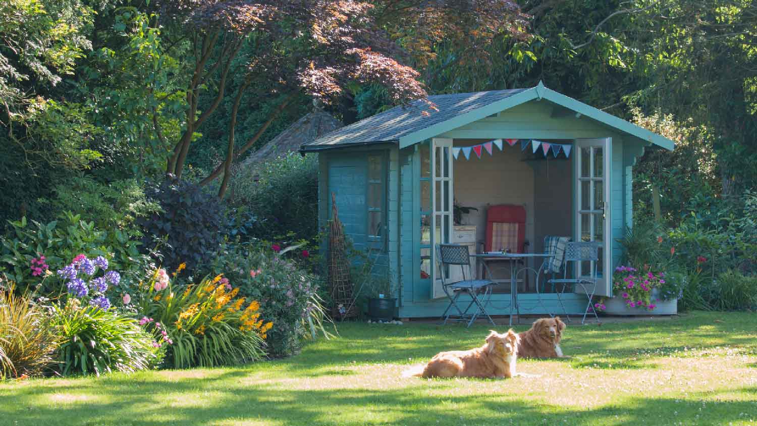 A summer house with two dogs laying in the trees shadow