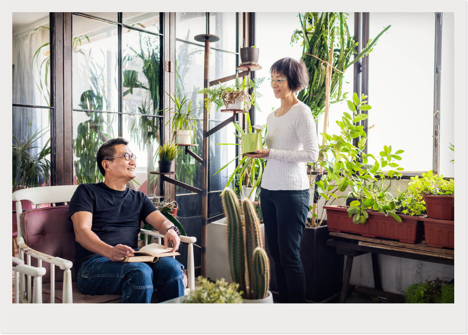 man and woman talking in sunroom with lots of plants