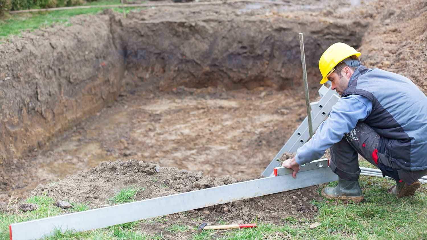 Professional pool contractor inspecting construction site 