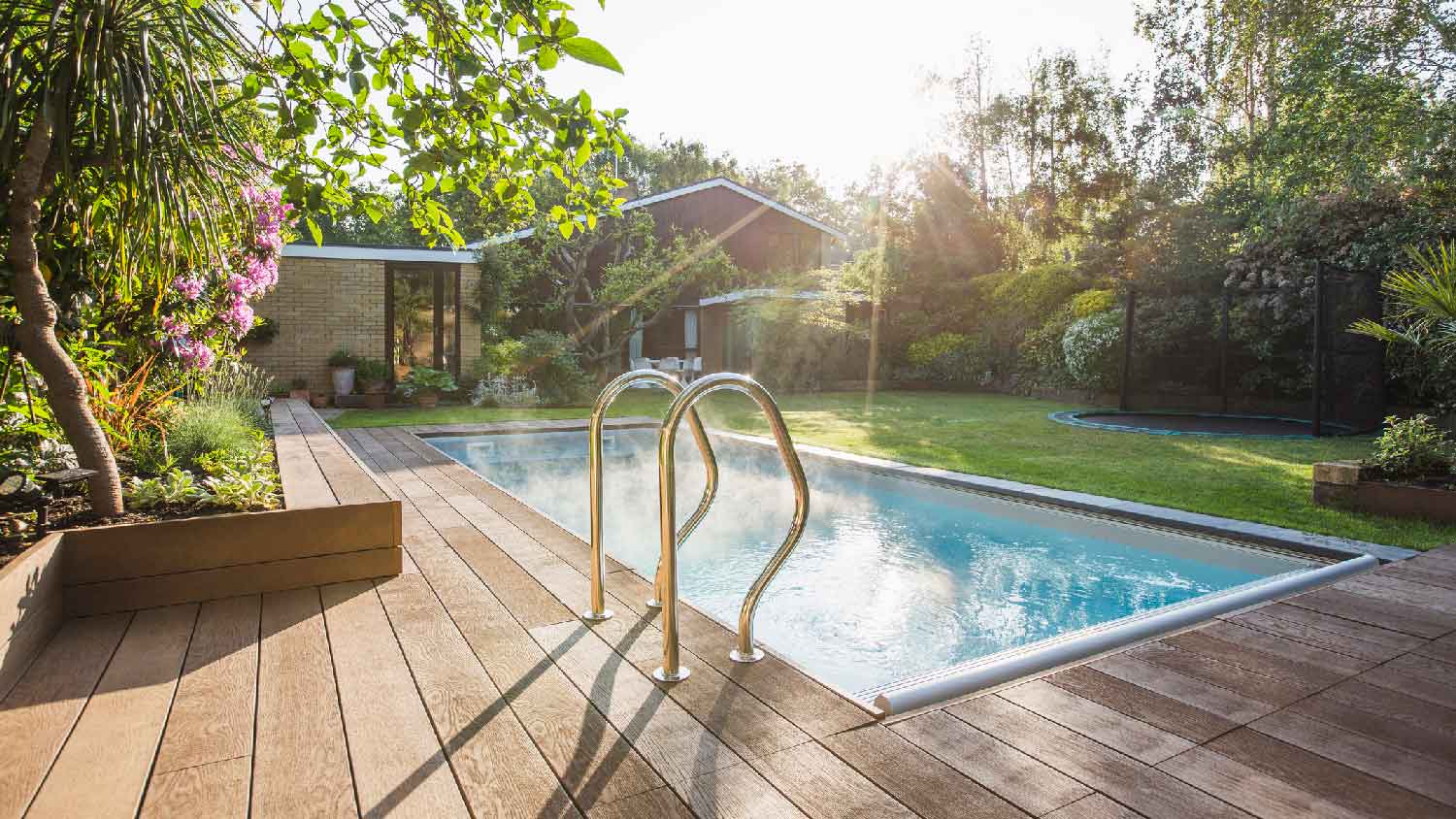 A swimming pool and a wooden deck in a house’s backyard