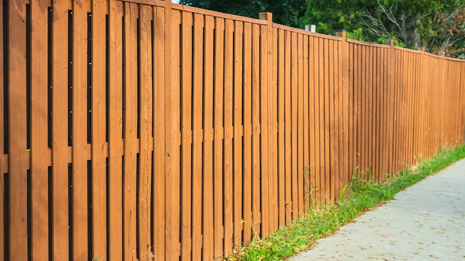 Tall wooden fence installed along the sidewalk