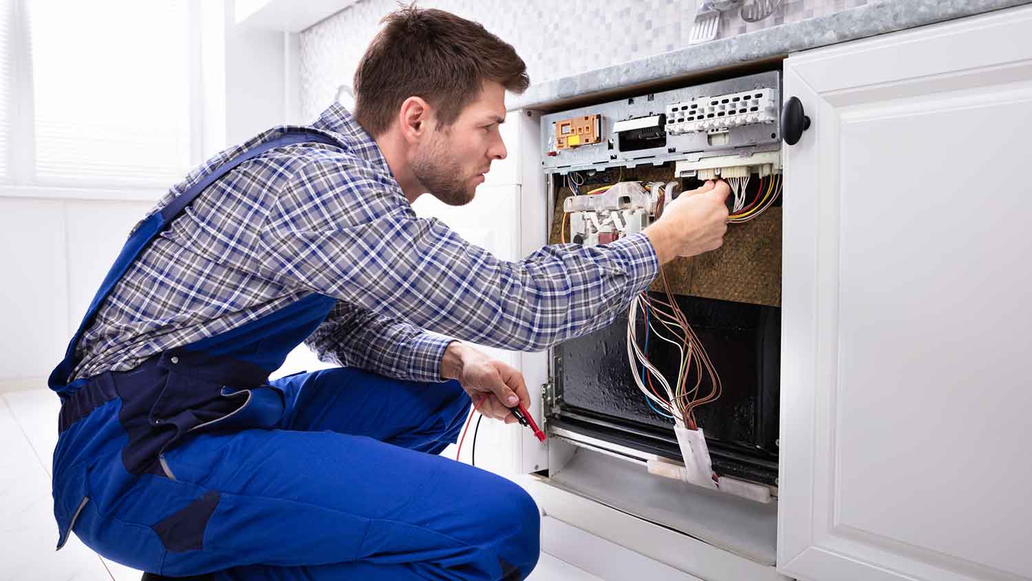 Technician checking dishwasher wiring