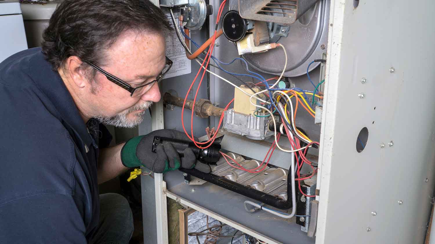 Technician inspecting gas furnace in the basement