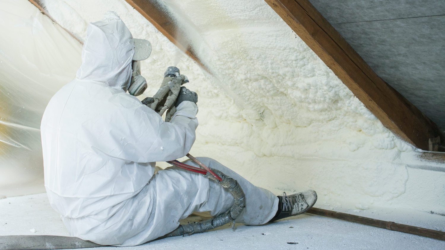 A professional laying coats of polyurethane spray foam