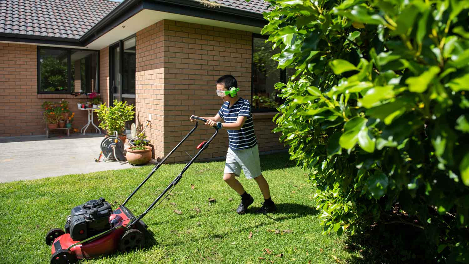 A teenage boy mowing the lawn