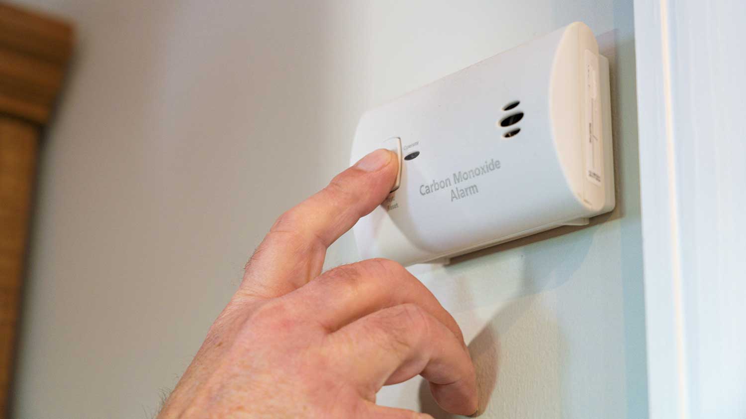 Hand pressing test button on a carbon monoxide detector