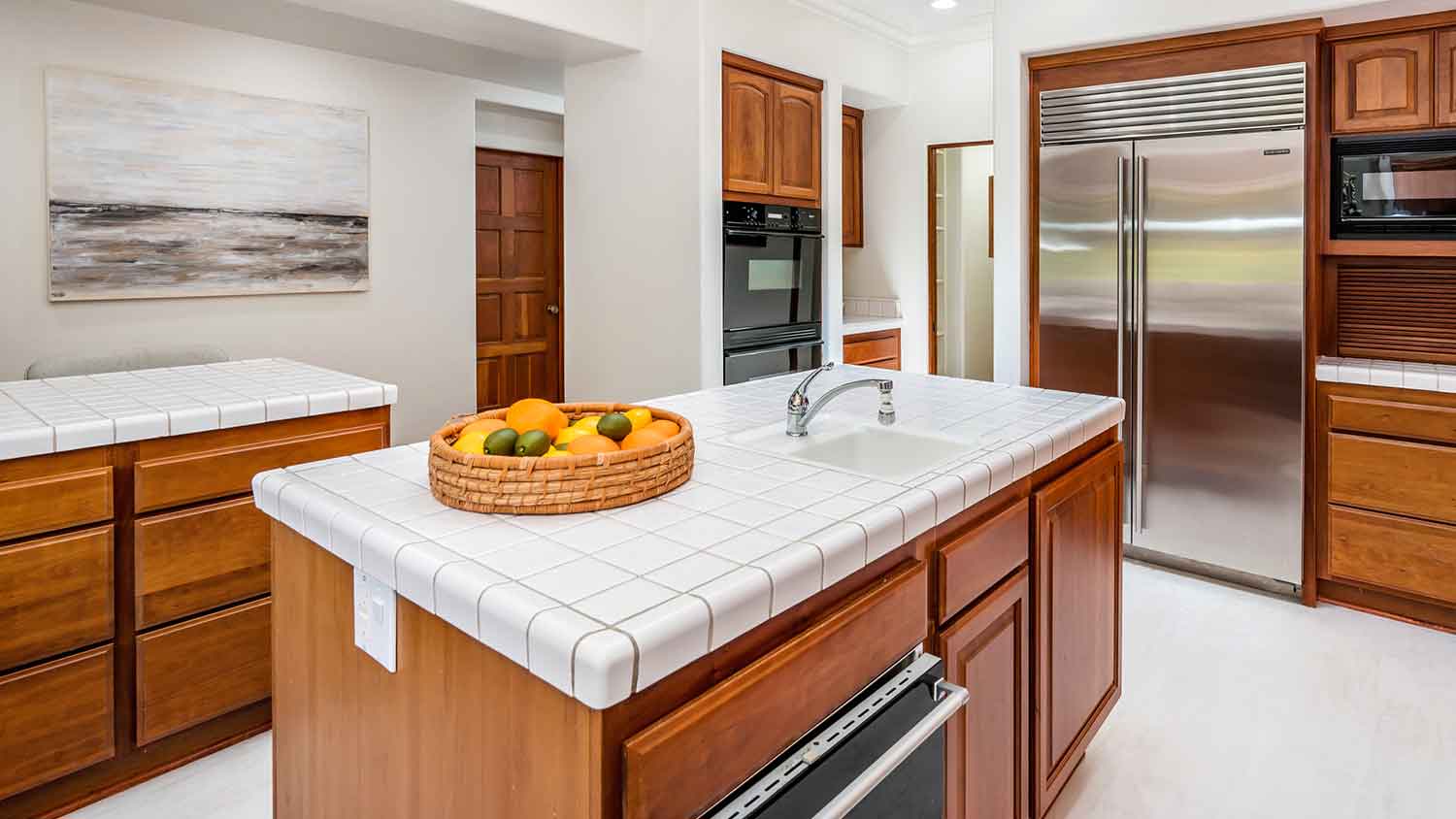 Spacious kitchen with tiled countertop and wooden cabinets