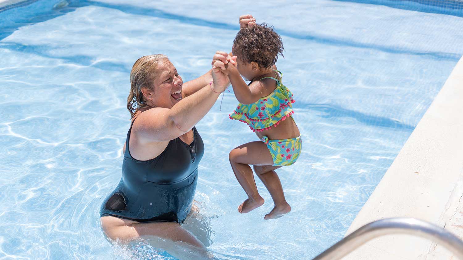 Toddler and grandma playing in the pool 