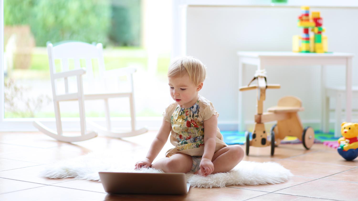 A toddler playing with a notebook on a tiled floor